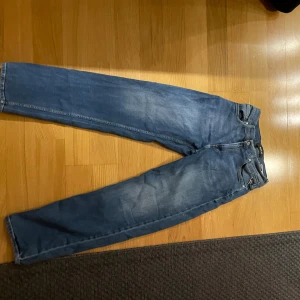 Blå Replay jeans relaxed fit 29 - Säljer ett par blå jeans från Replay i relaxed fit, storlek 29. Klassisk femficksmodell med snygga detaljer och läderpatch bak i midjan. Jeansen har raka ben och är tillverkade i slitstarkt denimtyg. Perfekta för en avslappnad och cool stil.