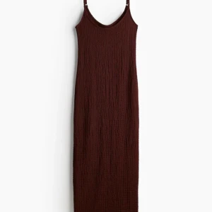 Mörkbrun långklänning med smala axelband - En stilren mörkröd långklänning med smala axelband och lätt strukturerat tyg. Klänningen har en rak passform och är ärmlös, perfekt för dig som gillar minimalistisk och elegant stil.