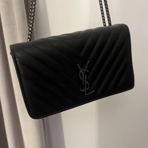 Svart quiltad axelväska  - Säljer en svart quiltad axelväska med kedjerem och klassisk logga framtill. Aldrig använd