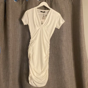 Bikbok Vit  klänning - En helt ny vit klänning från Bikbok. Prislappen finns kvar så den är aldrig använd. Kortärmad med scrunch på båda sidorna av klänningen så den är stretchig. 
