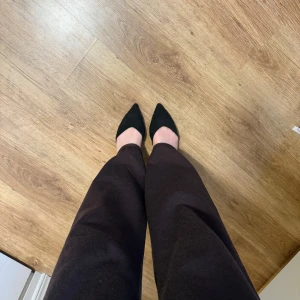 Svarta pumps med spetsig tå, strl 42 - Svarta pumps med spetsig tå och låg klack. Skorna har en elegant rem över hälen och är tillverkade i mocka-liknande material. Är i storlek 42 men jag har normalt storlek 40 och dessa passar mig bra. 