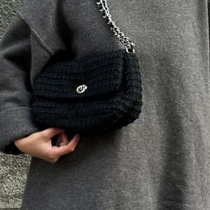 Svart stickad axelväska med kedja - Säljer denna super snygga svarta axelväskan med en stickad struktur☺️ jag säljer den för 600 då den har en liten vit märke inuti väskan☺️ men nypris på väskan är 900☺️kan även diskutera pris!!!!!