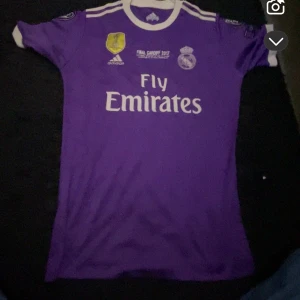 Real Madrid Ronaldo 7 Champions League tröja - Säljer en lila Real Madrid fotbollströja från Adidas, Champions League-finalen 2017 i Cardiff. Tröjan har Ronaldo 7 på ryggen, vita detaljer och tryck, samt officiella märken och loggor. Materialet är lätt och andas, perfekt för match eller träning. De är helt nya. Vet inte exakt storleken men jag har på mig S i allt så skulle kunna tänka mig att de är S 