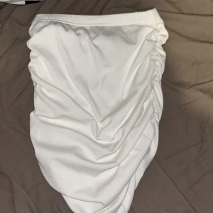 Vit ribbad kortkjol från SHEIN SXY - Supersnygg vit kortkjol från SHEIN SXY i ribbat material. Kjolen har en tight passform och cool rynkdetalj på sidan som ger en trendig look. Perfekt för dig som gillar stilrena och moderna plagg med det lilla extra.