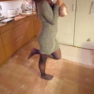 Glittrig silverklänning  - Snygg glittrig silverfärgad klänning från Bik Bok. Modellen är kort med långärmade ärmar, omlott-v-ringning och rynkade detaljer längs sidorna. Perfekt för dig som vill sticka ut med en festlig look. Materialet är mjukt och stretchigt syntet. Endast använd 1 gång, så den är i ett fint skick, säljer då jag inte använder den längre💕 hör av er vid frågor 