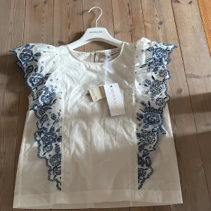 Vit blus med blå broderi från Monnalisa - Superfin vit blus från Monnalisa med volangärmar.                                                           Endast testad ny pris 1100💕