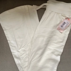 Vita mjukisbyxor från Nelly  - Vita tighta utsvängda mjukisbyxor från Nelly i mjukt material med bred resår och snörning i midjan. Helt oanvända med lapp kvar.