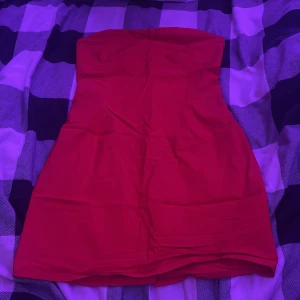 2 st Röd axelbandslösa kortklänningar från Bik Bok - Säljer en röd axelbandslös kortklänning från Bik Bok i storlek M. Klänningen har en figurnära passform och en slits baktill för extra rörelsefrihet. Materialet känns mjukt och följsamt mot kroppen. 