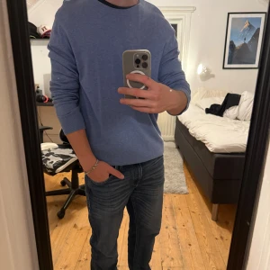Blå stickad tröja från H&M slim fit - Säljer en stilren blå stickad tröja från H&M i slim fit-modell. Tröjan har rund halsringning, ribbade muddar och är långärmad. Perfekt för dig som gillar en clean och enkel look.
