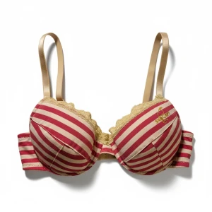 Randig röd och beige Snobben-bh 75B - Säljer en snygg BH med Snoopy/Snobben på från Seppälä. Den ärröd och beigea ränder, spetskant i gult och justerbara axelband. Kuporna är väldigt lätt vadderade och har urtagbara tunna kuddar. BHn har en gullig Snoopy-detalj på etiketten och är tillverkad i mjuk bomull med lite elastan för extra komfort. Är aldrig använd, kommer från ett konkurslager. Se även mina andra auktioner. Bundlerabatt på 20% vid flerköp.