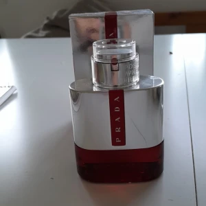 Prada parfym med röd detalj - Stilren parfym från Prada med modern design och röd detalj. Perfekt för dig som vill sticka ut med en exklusiv doft. Levereras med originalförpackning.cirka 48ml av 50 ml