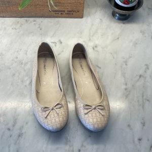 Beige ballerinaskor från Tamaris - beige ballerinaskor från Tamaris med diskret mönster och liten rosett framtill, i skinn