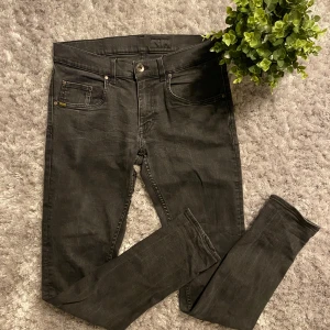Svarta Tiger of Sweden jeans - Jeansen har en defekt, som vissas tydligt på bild 5. De är en lite nött/urtvättat fläck där de har blivit lite missfärgning. Inget som syns vid användning. Annars väldigt fint skick  Storlek W31 L32 Tveka inte på att skriva till mig vid funderingar.  Modellen heter Tiger of Sweden ”Slim” Priset är inte hugget i sten