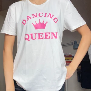 Vit Dancing Queen t-shirt - Vit t-shirt med rosa texten 'Dancing Queen' och en krona tryckt på bröstet. Klassisk rund hals och korta ärmar. Bara testad på nu för att fota. Skön och lätt i bomull, perfekt för dig som gillar rosa och Abbas låt🩷😀