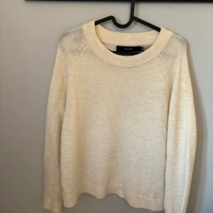 Beige stickad tröja från Vero Moda - Mysig beige stickad tröja från Vero Moda med rund halsringning och långa ärmar. Perfekt för lager-på-lager och enkel att matcha med jeans eller kjol. Tröjan har en klassisk passform och ribbade muddar vid ärmslut och nederkant.
