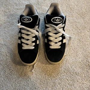 Svarta Adidas sneakers med vita ränder - Säljer ett par klassiska svarta Adidas sneakers. Knapt använda. Storlek 48 men passar 47,5