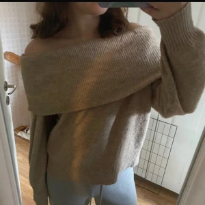 Beige offshoulder stickad tröja - Supermysig beige stickad tröja med bred offshoulder-ringning och långa ärmar. Perfekt för lager-på-lager och chill höst- eller vinterstil. Mjuk och skön, passar till både jeans och mjukisbyxor.