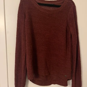 Vinröd stickad tröja från ONLY - Mysig vinröd stickad tröja från ONLY i storlek L. Tröjan har rund halsringning, lång ärm och är tillverkad i en blandning av akryl och polyamid. Perfekt för lager-på-lager och chill höst- och vinterstil.