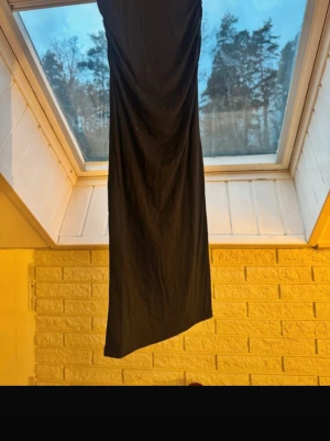 Mörkblå långkjol i bomull - Säljer en svart långkjol med rak och enkel siluett. Kjolen är tillverkad i mjukt bomullstyg och har en klassisk look utan mönster eller detaljer. Perfekt för dig som gillar minimalistisk stil och vill ha en kjol som är lätt att matcha med olika toppar.