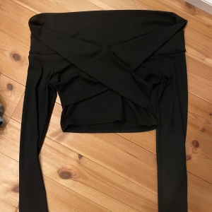 Svart offshoulder topp från SHEIN - Säljer en svart ribbad offshoulder topp från SHEIN i storlek M. Toppen har långa ärmar och en croppad passform som sitter snyggt över axlarna. Perfekt för dig som gillar stilrena och trendiga plagg med lite edge.