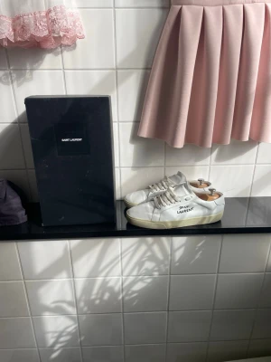 Saint Laurent skor - Säljer ett par stilrena vita sneakers från Saint Laurent. Svin bra skick lite små smutsiga, säljer då jag tröttnat och vill sälja. Priset går att diskutera, byten tas gärna! /Vilgot🎂