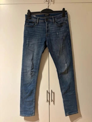 Jeans från Jack & Jones – Slim Glenn, toppenskick - Säljer ett par jeans från Jack & Jones i modellen Slim Glenn. De har en snygg slim fit som sitter bra utan att bli för tajt och funkar perfekt till både vardag och mer uppklädda outfits. Klassisk design som är lätt att matcha med hoodie, tröja eller skjorta. Jeansen är använda få gånger och i mycket fint skick, storlek 29/32