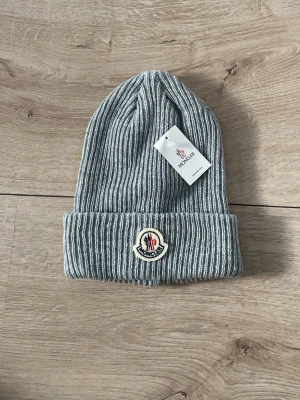 Moncler mössa - Säljer nu min gråa ribbade moncler mössa, fungerar perfekt nu till vintern för dig som vill se både stilren och elegant ut men också ha de där lilla extra och få blickar mot dig. Mössan är helt oanvänd och tagsen sitter kvar. Vid frågor eller liknande, va inte en främling, kontakta mig. Vänlig hälsning!