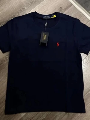 Marinblå Polo Ralph Lauren T-shirt  - Säljer denna stilrena, efterfrågade T-shirten från Polo Ralph Lauren. På T-shirten står det L men den passar som S. Riktigt utmärkt kvalitet och väldigt snygg som passar allt. Skriv gärna vid intresse och för mer information! Tveka inte på att skicka bud.