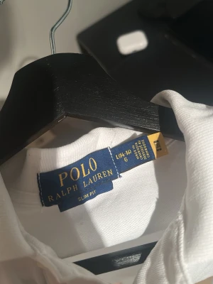 Vit slim fit piké från Polo Ralph Lauren - Fräsch vit pikétröja från Polo Ralph Lauren i slim fit-modell. Klassisk krage, korta ärmar och den ikoniska broderade loggan på bröstet. Tillverkad i mjuk bomull som är skön mot huden. Perfekt för dig som gillar stilrena och tidlösa plagg. Kom privat vid eventuella frågor!😀( cirka 175 på bilden) 