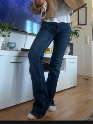 Blå bootcut jeans - Snygga blå jeans med bootcut-snitt som ger en schysst siluett. Jeansen har klassisk femficksdesign och är tillverkade i ett mjukt och slitstarkt denim-material. Perfekta för dig som gillar en tidlös look med lite extra attityd.
