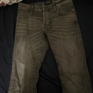 Grå slim jeans från Jack & Jones - De är 30/30. Säljer ett par gråa slim fit jeans från Jack & Jones, modell Glenn. Jeansen har klassisk femficksdesign, snygga sömmar på bakfickorna och en mörk tvätt som ger en cool vibe. Perfekt passform för dig som gillar smalare jeans.