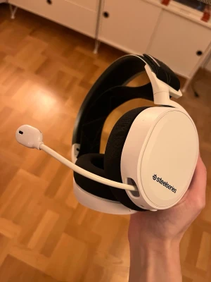 SteelSeries Arctis 7 - SteelSeries Arctis 7 trådlöst gamingheadset i vitt. Utrustat med bekväma öronkuddar, justerbart huvudband och infällbar mikrofon. Headsetet är i mycket fint skick utan synligt slitage. Perfekt för spel och kommunikation med hög ljudkvalitet och komfort.