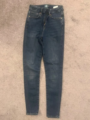 Mörkblå skinny jeans  - Snygga mörkblå skinny jeans med klassisk femficksdesign och smal passform. Jeansen har hög midja och är tillverkade i stretchigt denim för extra komfort. Perfekt för dig som gillar en tajt siluett och stilren look.