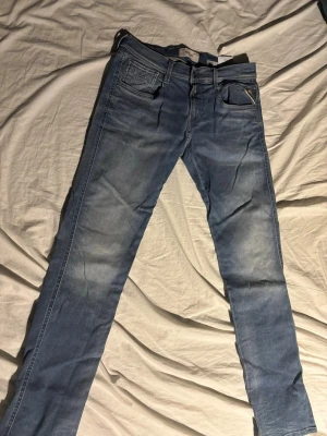 Replay Anbass blå jeans - Snygga blå Replay Anbass jeans med klassisk femficksdesign och läderpatch bak i midjan. Jeansen har en slim passform och är tillverkade i mjukt jeansmaterial med lätt tvättad look. Perfekta för dig som gillar stilrena och moderna jeans. W29 L32