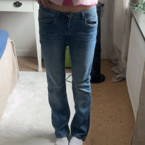 Blå raka jeans midwaist - Säljer ett par klassiska blå jeans med rak passform och low waist. Jeansen har fem fickor, dragkedja och knapp framtill. Perfekta för dig som gillar en enkel och tidlös stil. Materialet är jeans och färgen är mellanblå. Midjemått: 37cm. Jag är 167cm. 