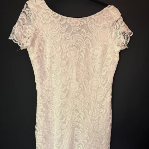 Vit spetsklänning från Bubbleroom - Superfin vit kortklänning från Bubbleroom med blommigt spetsmönster och v-ringning i ryggen. Klänningen har korta ärmar med spetsdetaljer och figurnära passform. Perfekt för sommarens alla tillfällen!