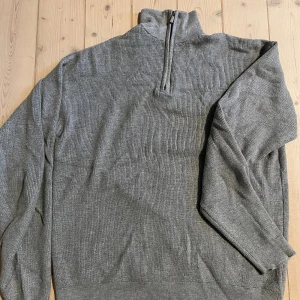 Half zip tröja grå  - Pris kan diskuteras, skriv för mer bilder! Snygg grå ribbad polotröja med half zip-dragkedja i halsen. Tröjan har lång ärm och en hög krage som ger en clean och stilren look. Perfekt för lager-på-lager och passar till både jeans och chinos.
