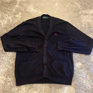 Cardigan från Polo Ralph Lauren - Mörkblå cardigan från Polo Ralph Lauren i storlek S. Den är använd men har definitivt mer att ge. Hör gärna av er vid funderingar!