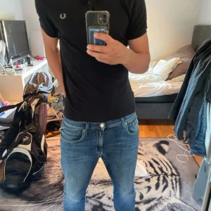 Svart Fred Perry pikétröja - Svart pikétröja från Fred Perry med klassisk krage och korta ärmar. Tröjan har den ikoniska Fred Perry-loggan broderad på bröstet och är gjord i mjuk bomull. Perfekt för dig som gillar stilrena och tidlösa plagg.