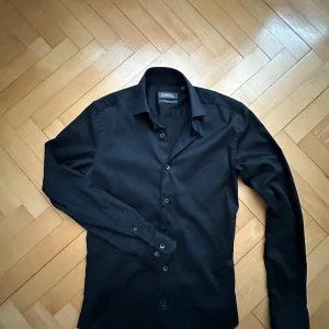 Svart skjorta från Dressmann - En stilig svart skjorta från Dressman i premium cotton👌Slimfit och riktigt stilig, skick 7/10🤝Hör av dig vid intresse.