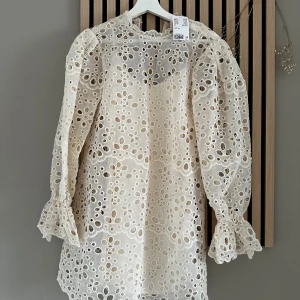 Vit spetsklänning med puffärm XS - Superfin vit kortklänning i bomull med broderade blommor och hålmönster. Klänningen har långa puffärmar med volang vid ärmslut och rund halsringning. Nypris 699! Sprillans ny endast testad.