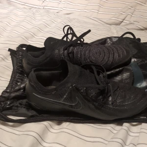 Svarta Nike fotbollsskor med snörning - Säljer ett par Svarta Nike phantom GX 2 ELITE  fg, pågrund av för stor storlek. Skorna är i storlek 42 och är använd 3 gånger på gräs. Jag köpte dem för 1900 kr men säjer dem för 1500 kr