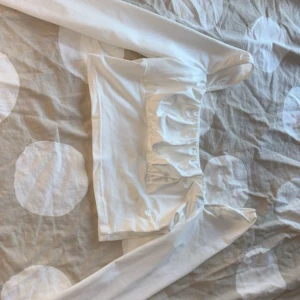 Vit långärmad topp från SHEIN - Säljer en vit långärmad topp från SHEIN i storlek M. Toppen har en croppad passform med rynkade detaljer framtill och är tillverkad i ett mjukt, stretchigt material. Perfekt för dig som gillar stilrena och trendiga plagg.
