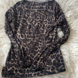 Leopardmönstrad långärmad meshtröja - Säljer en tunn och stretchig långärmad meshtröja från instimissmi  med leopardmönster i bruna och svarta toner. Perfekt att styla lager på lager eller som statement-piece. Tight passform och rund halsringning.