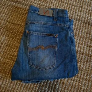 Blåa Nudie Jeans W33/L32 - Dessa är ett par otroligt snygga och väl omskötta Nudie Jeans i storlek W33/L34 och modell Dude Dan som är uppsydda till W33/L32 inne i Nudies Butik. Alltså är nya storleken Length 32. Jeansen sitter straight och har en material blandning av 99% Bomull och 1% Elastan. 💸 Priset är disskuterbart💸