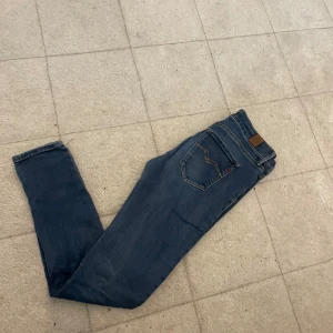 Replay jeans  - Snygga blå jeans från replay med klassisk femficksdesign och smal passform. Jeansen har en mörkblå tvätt och detaljerade sömmar på bakfickan. Perfekta för en stilren och avslappnad look.