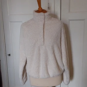 Vit fluffig fleece från H&M - Supermjuk och fluffig vit fleece-tröja från H&M med hög krage och halv dragkedja med tryckknappar. Perfekt för kyliga dagar, har lång ärm och loose passform. Enkel att matcha och riktigt cozy vibe.