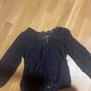 Svart spetsblus från NLY Icons - Säljer en svart blus från NLY Icons i storlek S. Blusen är helt i spets med blommigt mönster och har långa ärmar. Perfekt för dig som gillar detaljer och vill ha en snygg topp med transparent känsla och romantiska vibbar.