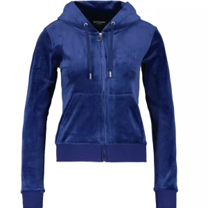 Blå velour hoodie från Juicy Couture - Säljer en blå hoodie från Juicy Couture i mjuk velour med dragkedja framtill, huva med snörning och broderad logga på bröstet. Tröjan har långa ärmar och ribbade muddar samt känguruficka. Perfekt för en chill och trendig look. De två silver sakerna på snörena har lossnat💕 pris kan diskuteras