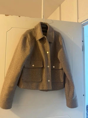 Beige jacka från ZARA  - Säljer en beige ”jacka” från ZARA med stora fickor framtill och knappar i silver. Jackan har klassisk krage och raka ärmar, perfekt för lager-på-lager. Enkel och stilren design som passar till många outfits. Passar till höst eller våren, lite oversize i stilen så perfekt till en tight outfit 😍passar en S